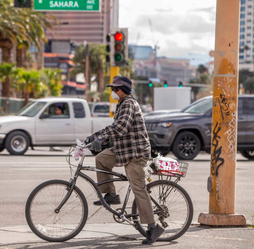 A man bicycles wearing a face mask along West Sahara Avenue on Saturday, March 14, 2020 in Las ...