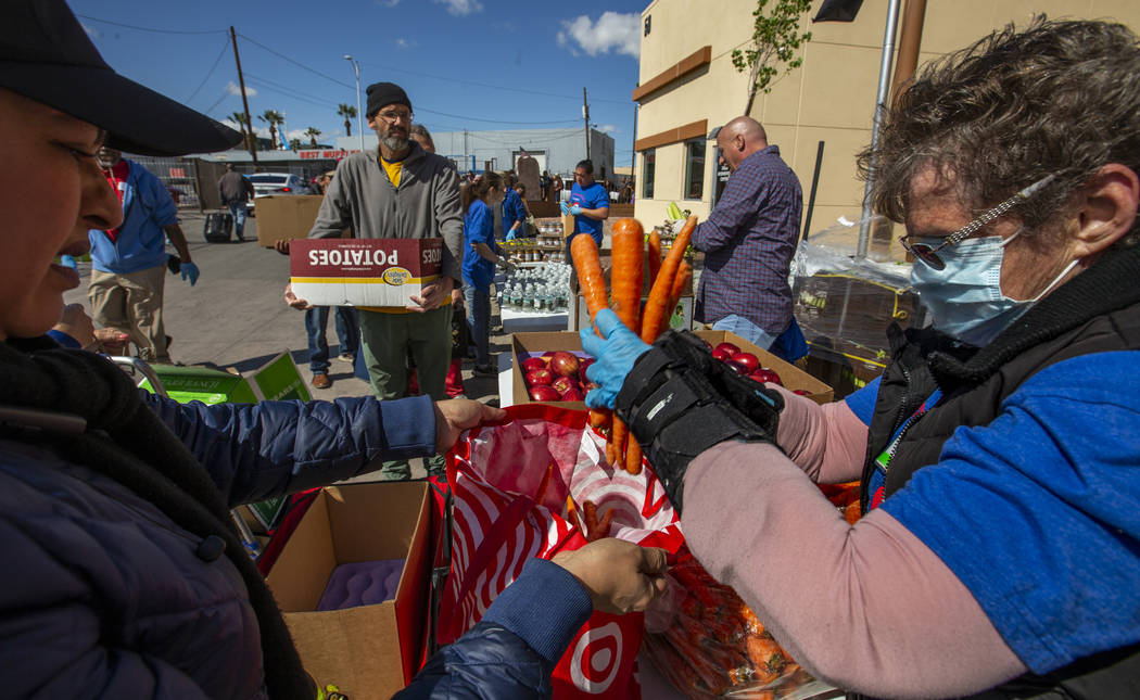 Christina Bailey, right, helps distribute carrots to those in need at SHARE Village Las Vegas o ...
