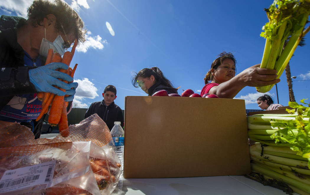 Christina Bailey, left, helps distribute carrots to those in need at SHARE Village Las Vegas on ...