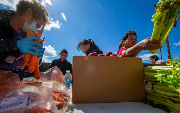 Christina Bailey, left, helps distribute carrots to those in need at SHARE Village Las Vegas on ...