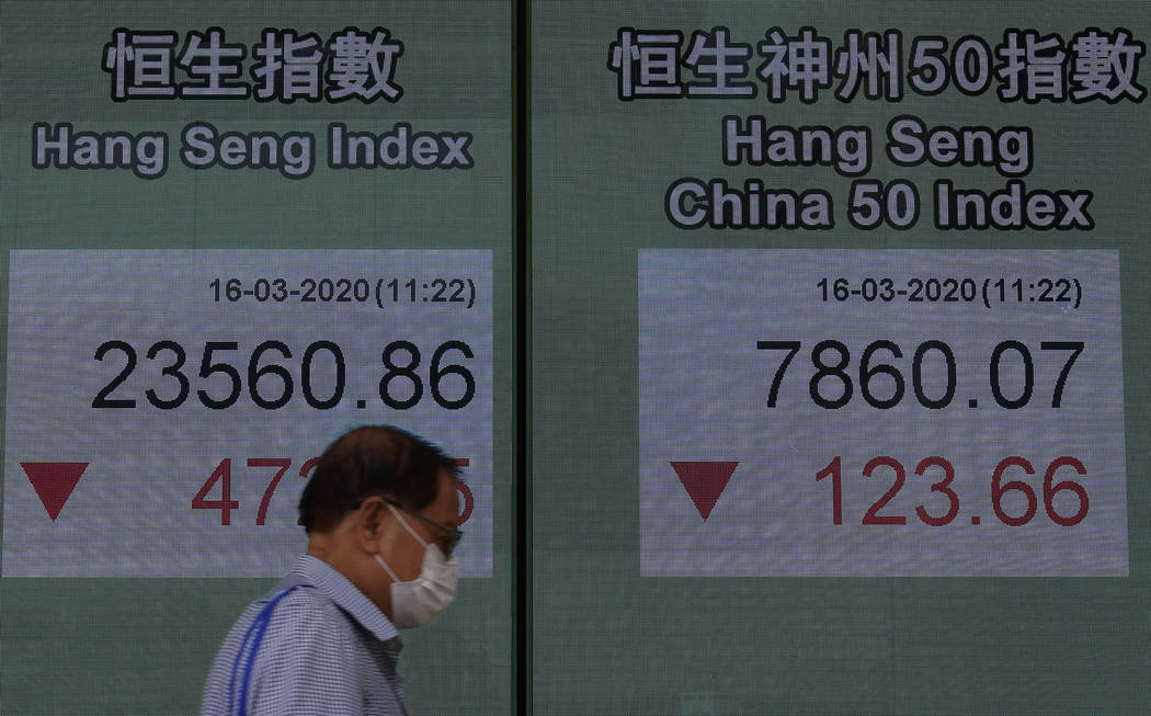 A man wearing face mask walks past a bank electronic board showing the Hong Kong share index at ...