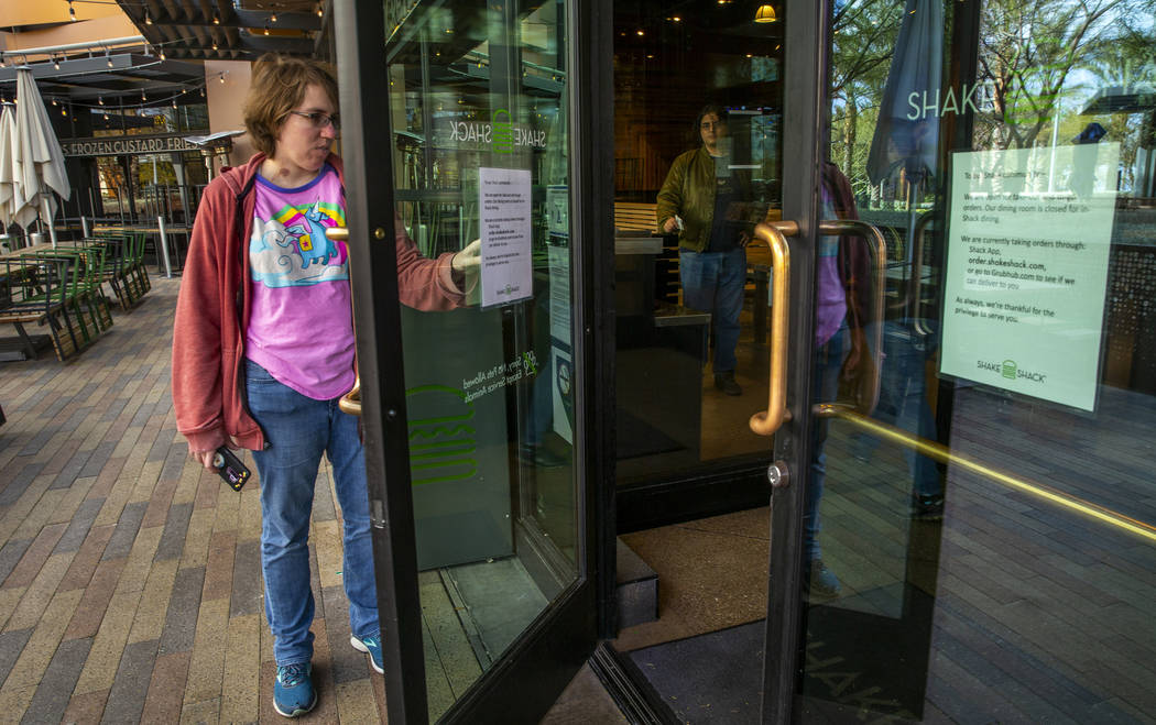 A Shake Shack customer reads the sign outside stating just carryout for the time being at Downt ...