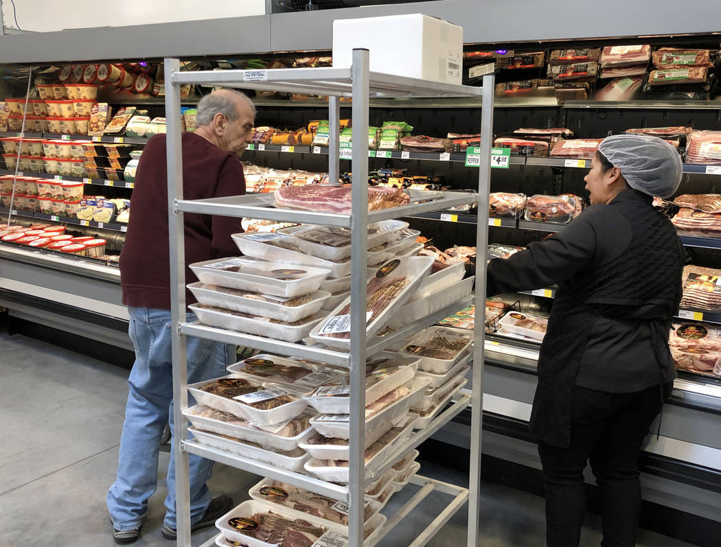 Nina Lopez, right, deli department manager, assists a customer as she stocks meat products at W ...