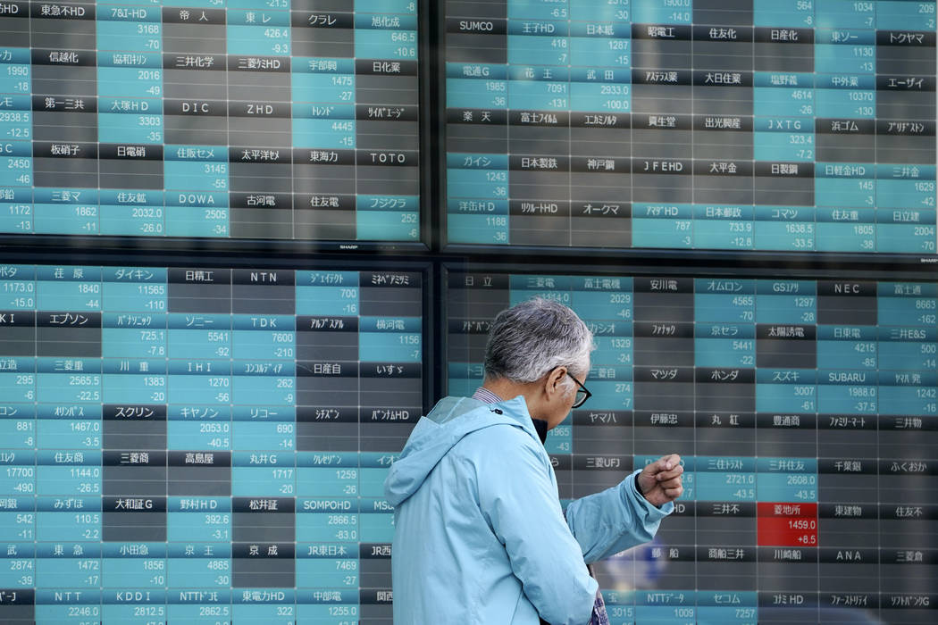 A man walks past an electronic stock board showing Japan's Nikkei 225 index at a securities fir ...