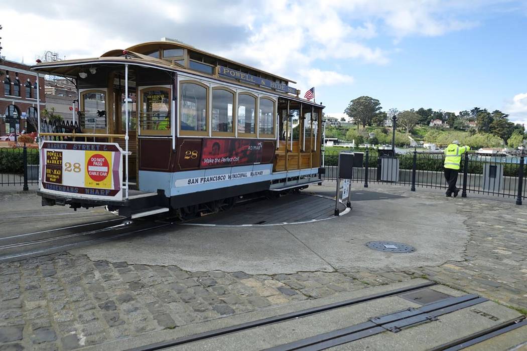 A cable car operator looks out toward the Golden Gate Bridge while standing at the near-empty H ...