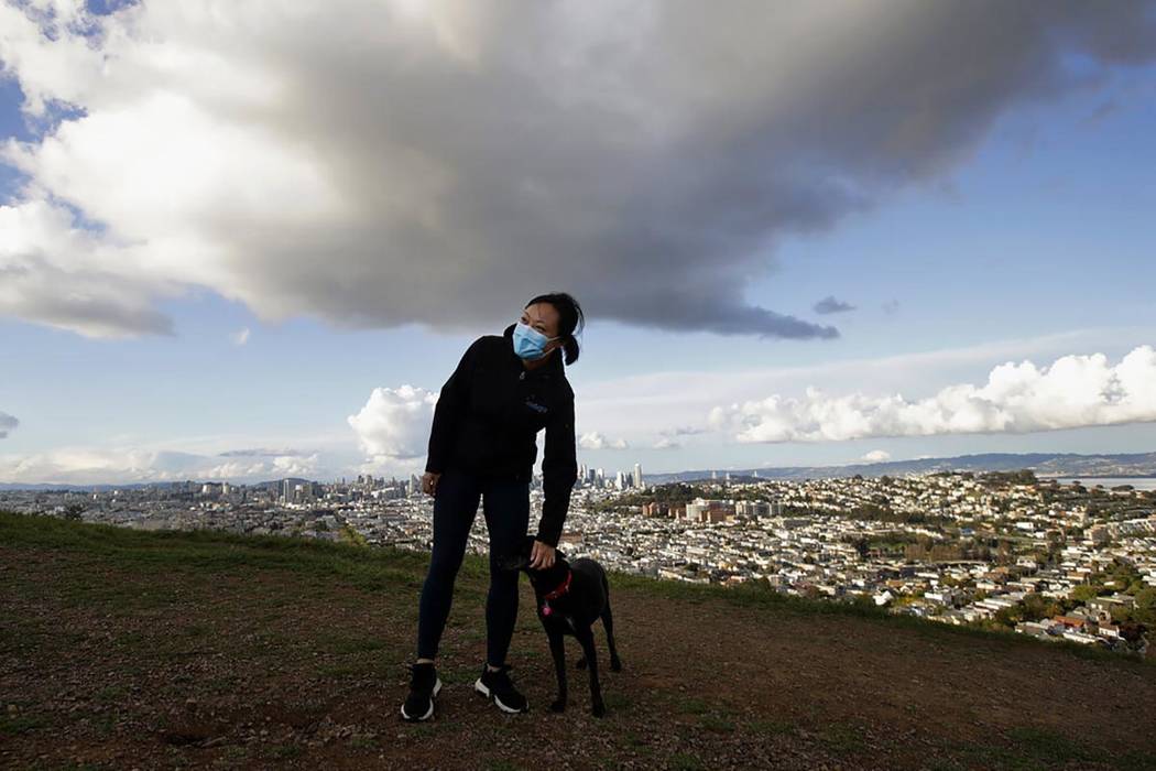 Lisa Wang wears a mask while walking her dog Rooney on Bernal Heights Hill in San Francisco, Mo ...
