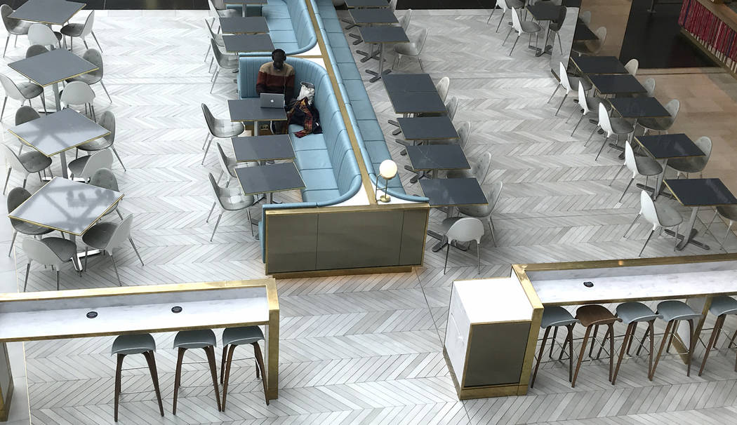 A man sits alone at a coffee shop area at a shopping centre in London, Tuesday, March 17, 2020. ...