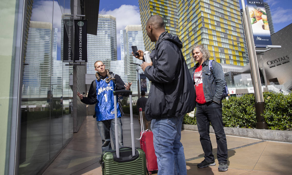 Raven Gee, left, and Max Bowe, from Oakland, Calif., take photos with a snake on the Strip on T ...