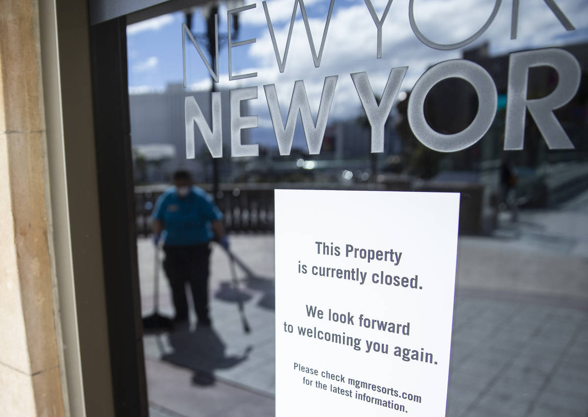 Cleaning staff work outside the doors to New York-New-York where closed signs are posted due to ...