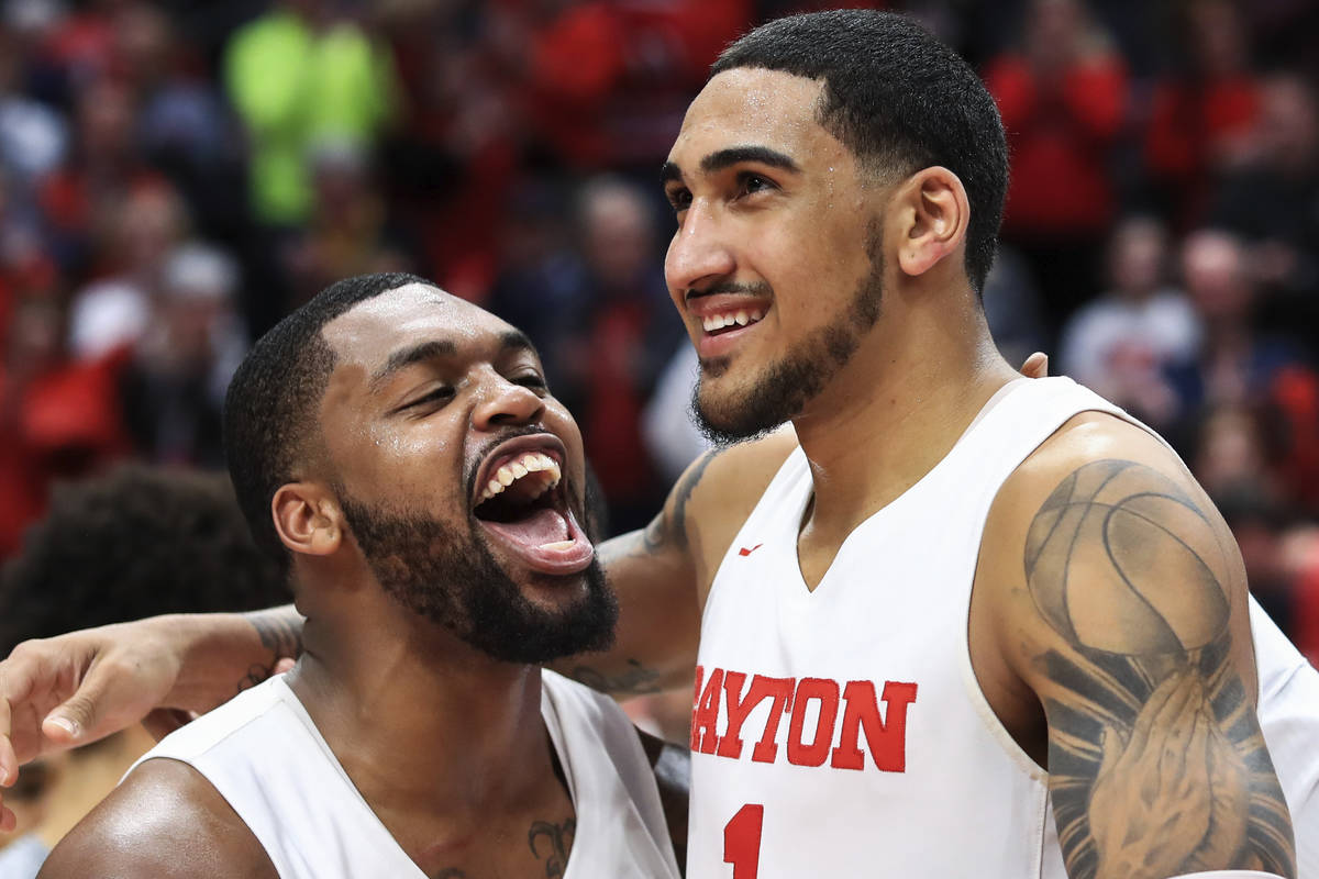Dayton's Trey Landers, left, reacts with Obi Toppin, middle, as he celebrates scoring his 1,000 ...