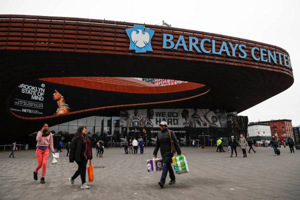 FILE - In this March 12, 2020, file photo, pedestrians walk past the Barclays Center, which is ...