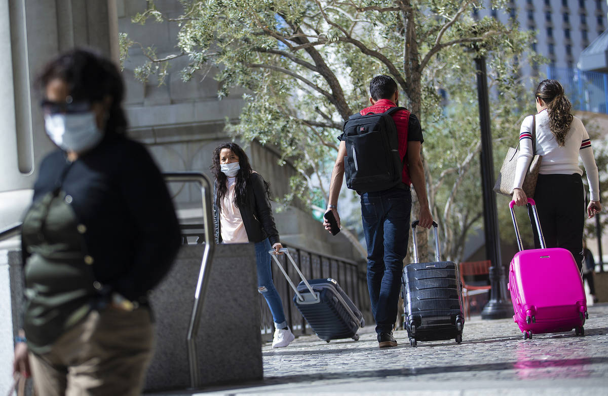 Tourists wearing medical masks make their way along the Strip on Tuesday, March 17, 2020, in La ...