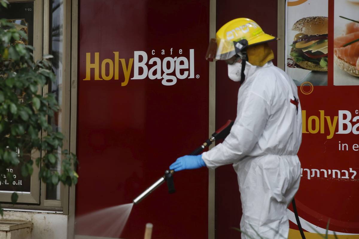 ‏An Israeli firefighter sprays disinfectant as a precaution against the coronavirus in M ...