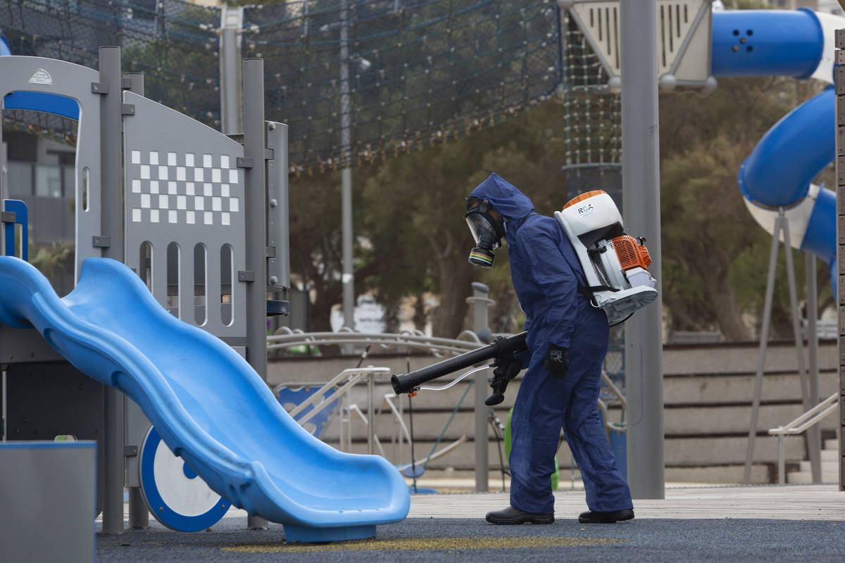 A worker sprays disinfectant as a precaution against the coronavirus at a playground in the cen ...