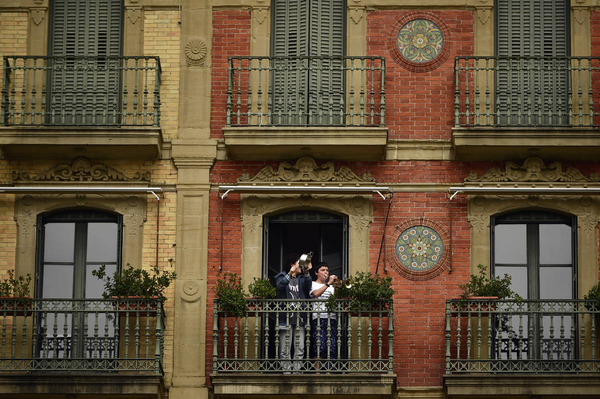 A young boy plays his trumpet from a balcony, in Pamplona, northern Spain, Wednesday, March 18, ...