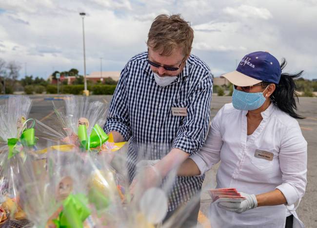 Volunteer Gary Perkins, left, and Demi Hou, owner and operator of Demi's Gift Baskets, add groc ...
