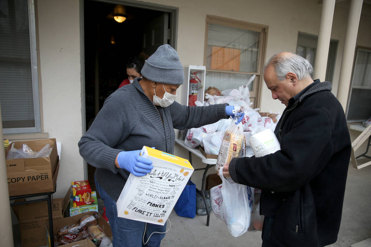 Cynthia Brooks, 66, a resident volunteer at Desert Plaza Apartments, right, gives food to Danie ...