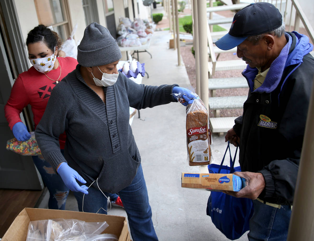 Cynthia Brooks, 66, a resident volunteer at Desert Plaza Apartments, center, gives food to Geor ...