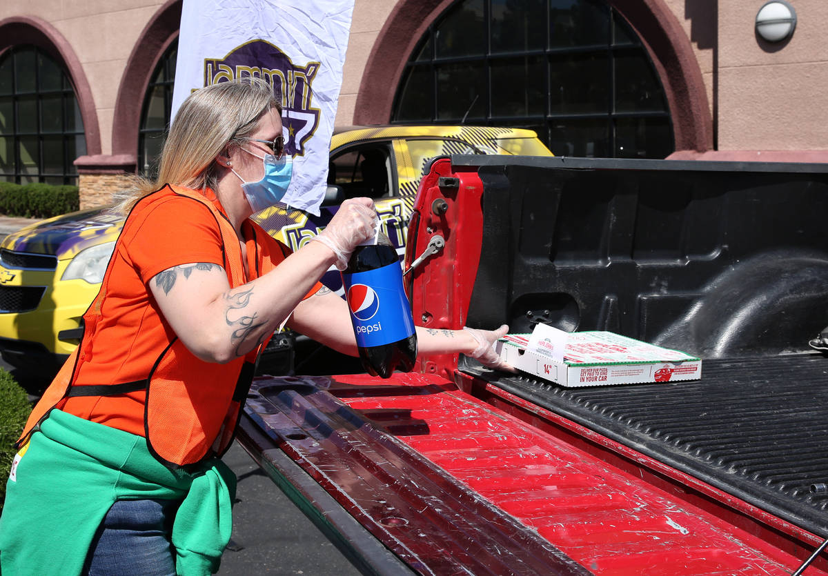Katey Powell, district manager at Papa Jone's Pizza Las Vegas, places a box of pizza and a soft ...