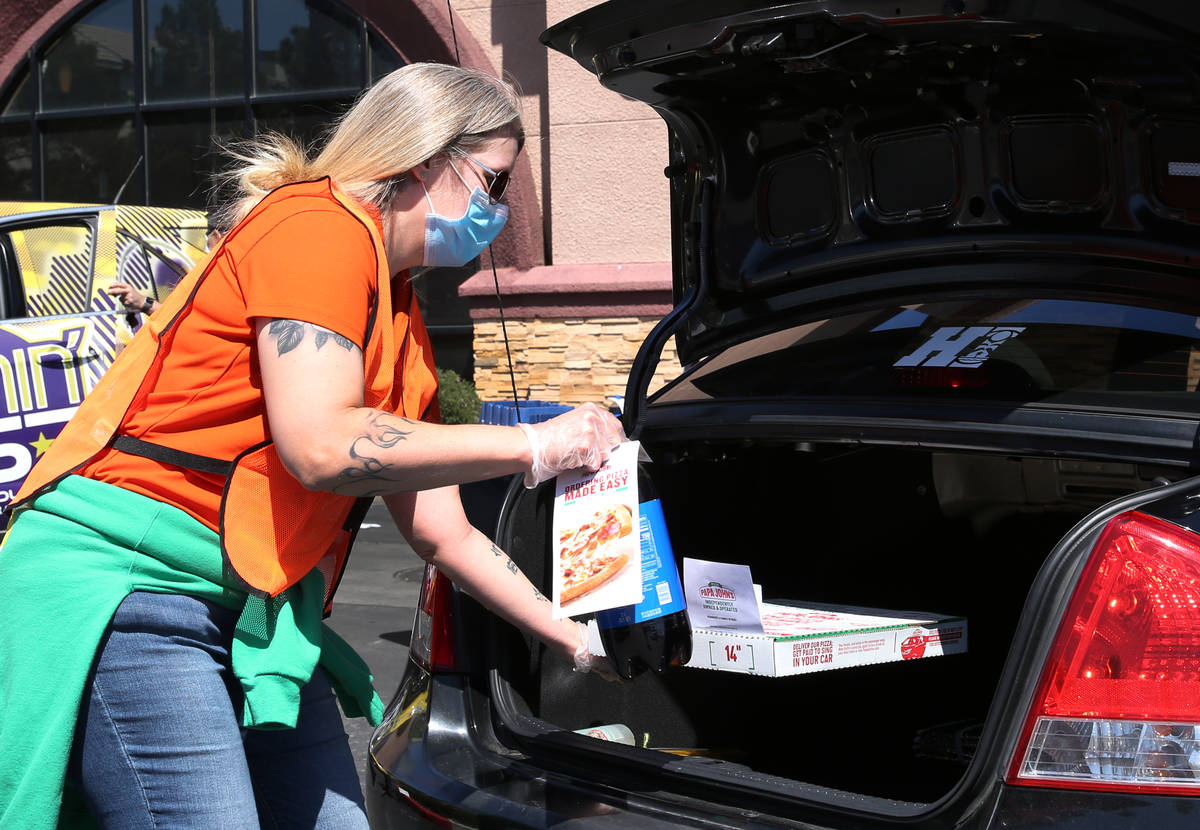 Katey Powell, district manager at Papa Jone's Pizza Las Vegas, places a box of pizza and a soft ...