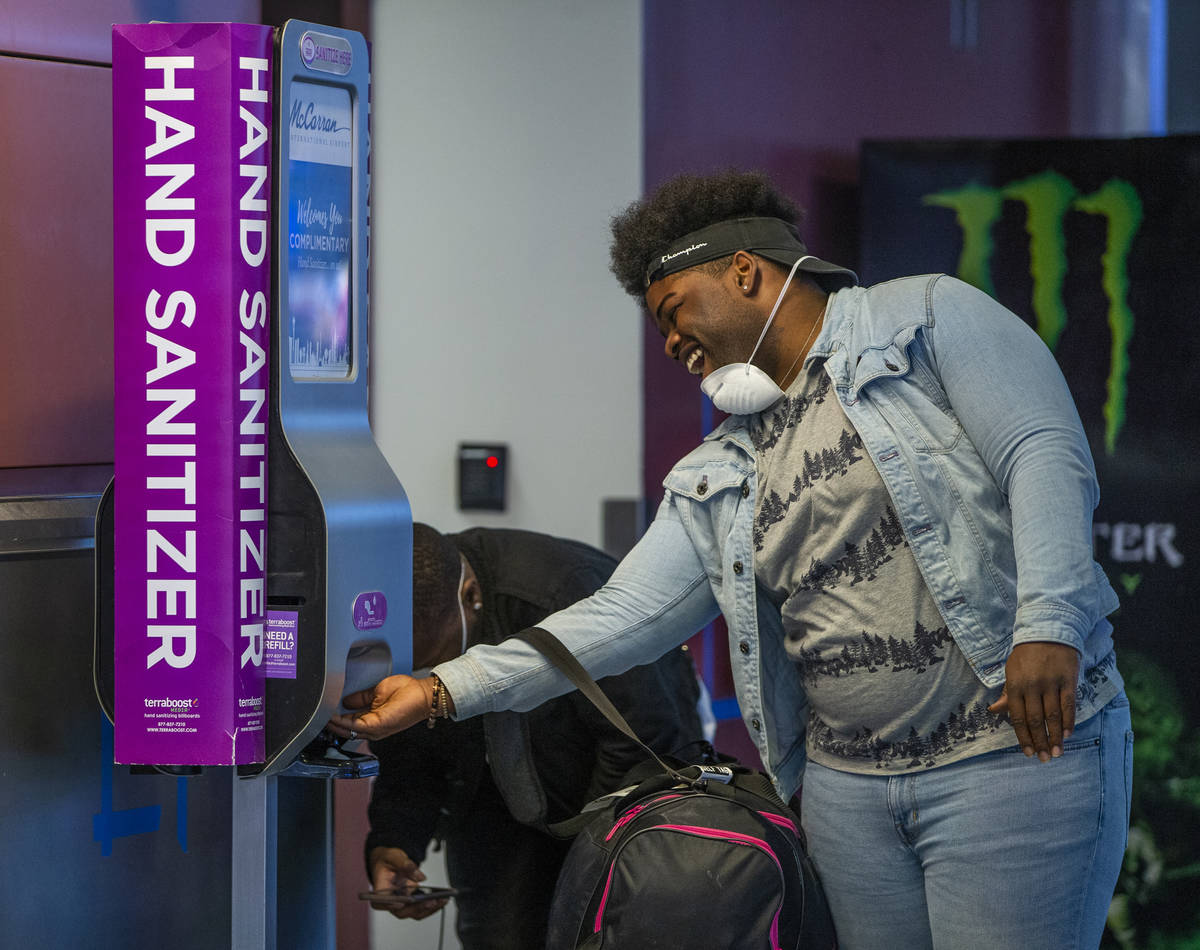 Masked passenger Daleonne Clark of Houston laughs with a friend while getting some hand sanitiz ...