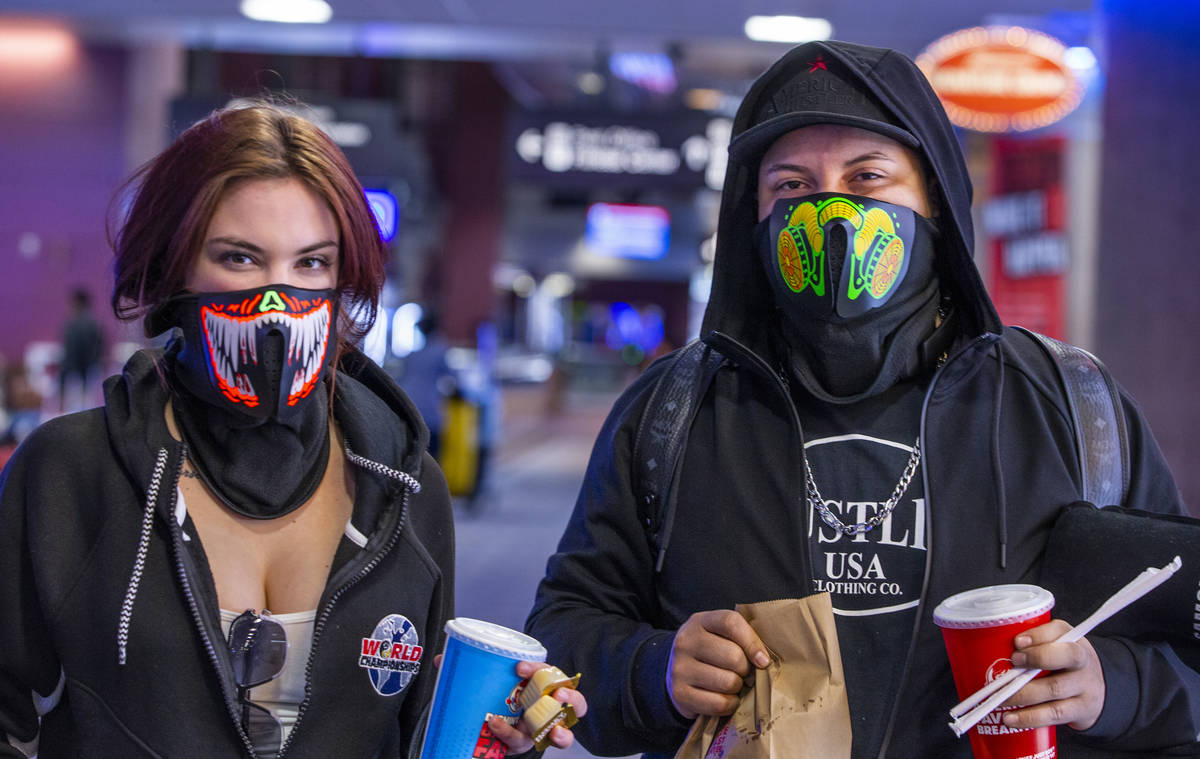 Passengers Sarah Lloyd and Johnny Calix of Orlando wear lighted masks in Terminal 1 while getti ...