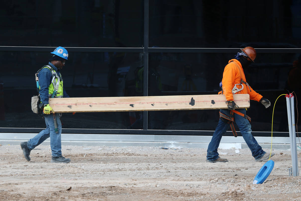 Workers carry a board at the Raiders Allegiant Stadium construction site in Las Vegas, Wednesda ...