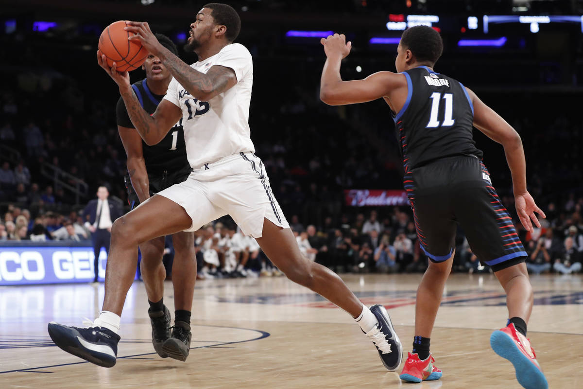 Xavier forward Naji Marshall (13) drives between DePaul guard Charlie Moore (11) and forward Ro ...