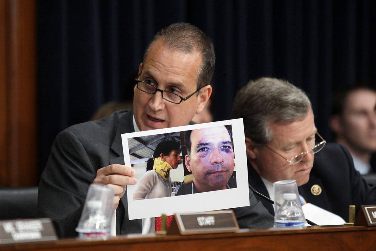 FILE--Rep. Mario Diaz-Balart, R-Fla. holds up an image of an American he claims was beaten in C ...