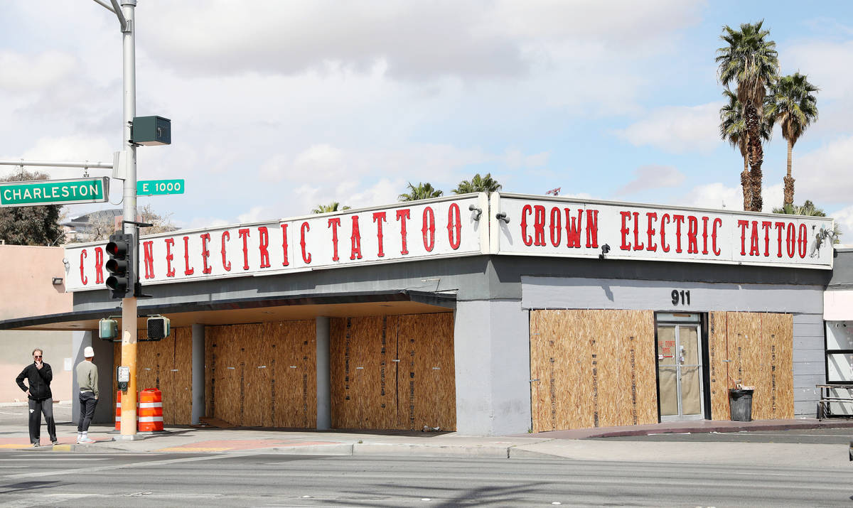 Pedestrians walk pass the recently boarded Crown Electric Tattoo Co. located on 911 East Charle ...
