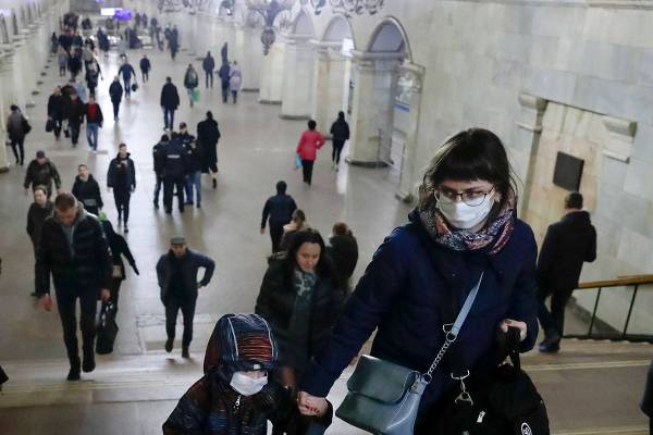 A woman with her child wear medical masks walk inside the Komsomolskaya Metro (subway) station ...