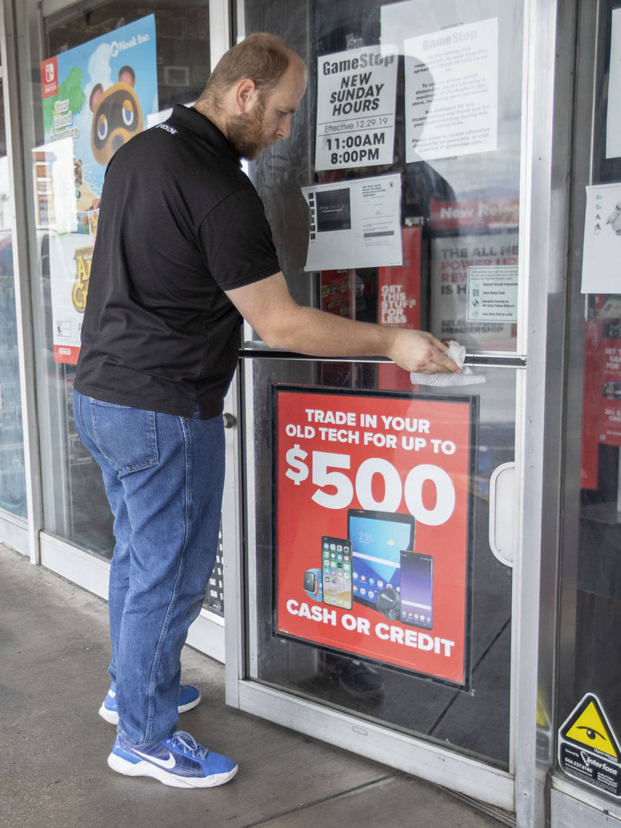 Eathan Upchurch wipes the door handle of the GameStop store at 2119 East Lake Mead Boulevard, w ...