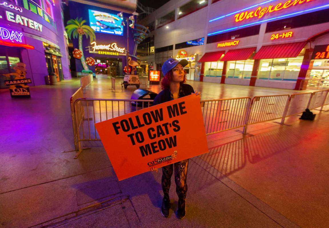 Kat V holds a sign advertising The Cat's Meow karaoke bar in downtown Las Vegas, where the stre ...