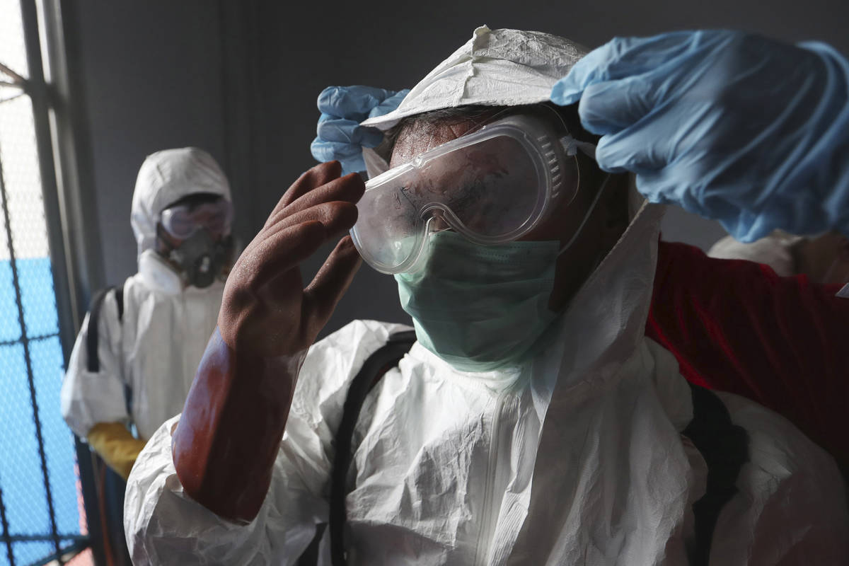 A member of Indonesian Red Cross receives assistance from a colleague to adjust his protective ...