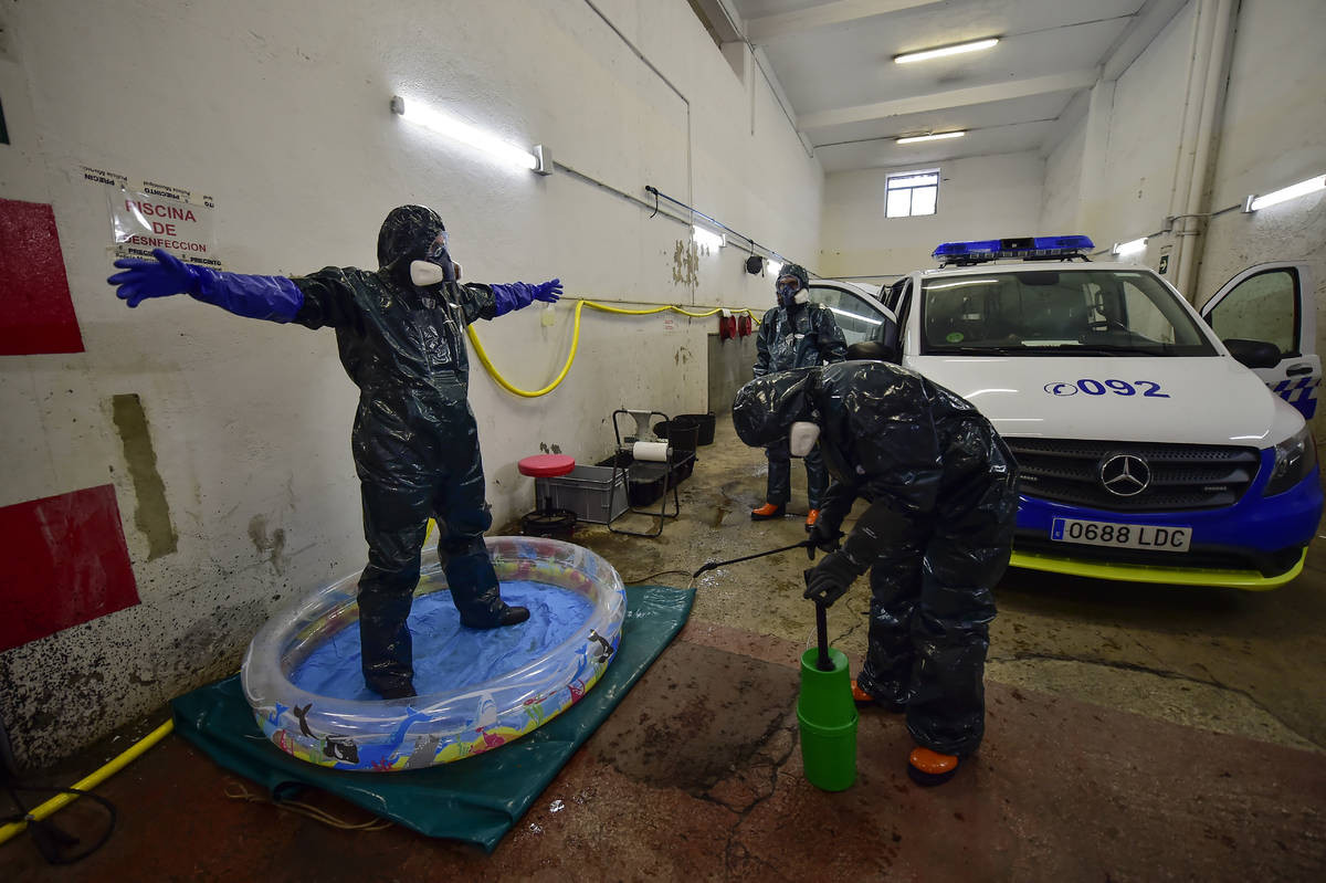 Volunteer workers of Search and Rescue (SAR) with special equipment, disinfect a volunteer whil ...