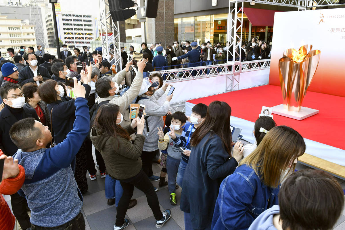 People gather to take a look at Olympic flame on display in Sendai, Miyagi prefecture, north of ...