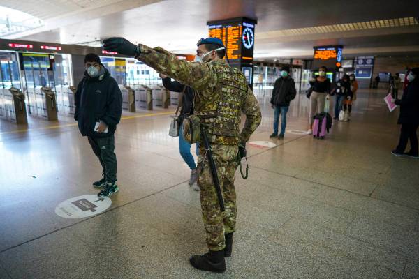 A soldier gives indications to passengers as they line up to have their travel documents checke ...