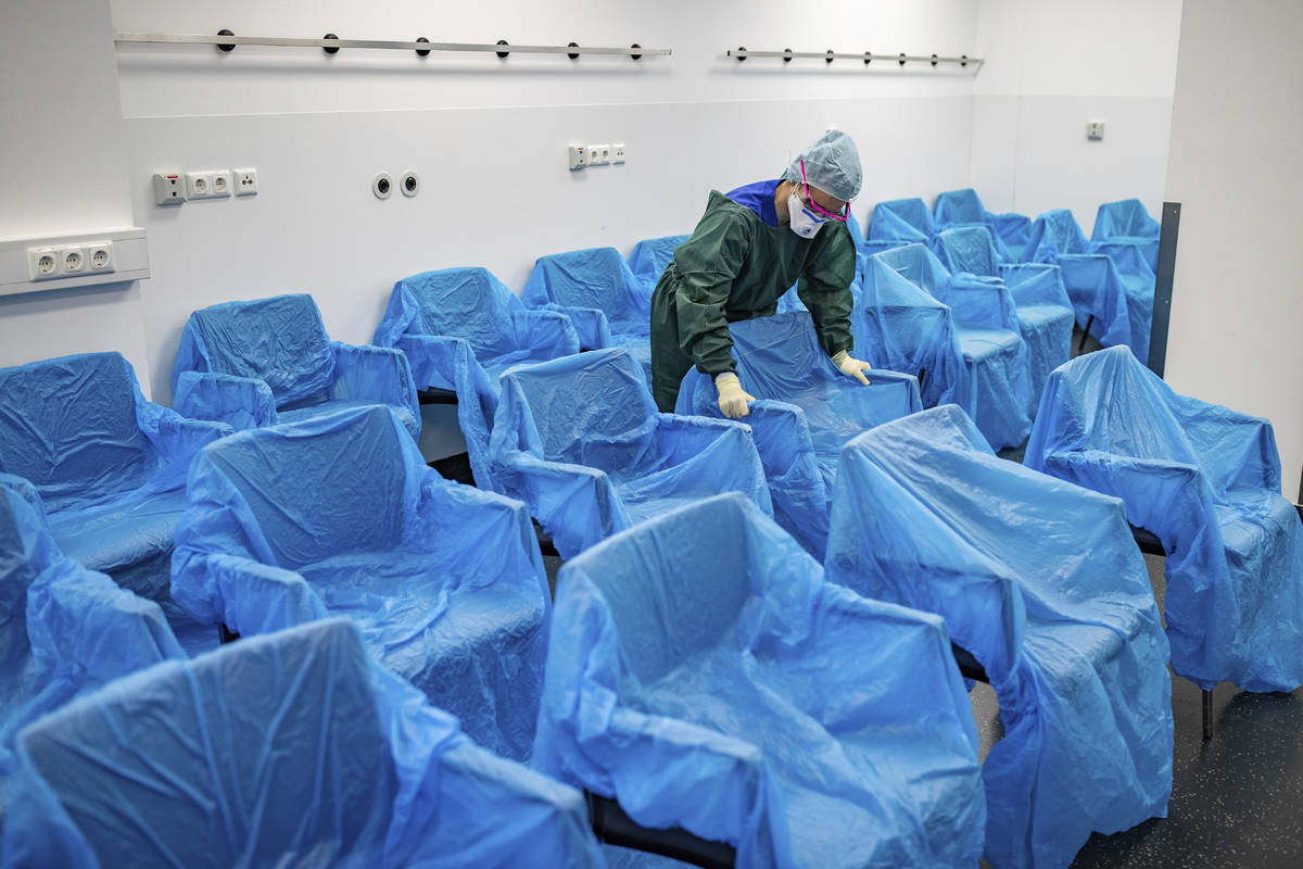 A nurse assembles plastic-wrapped chairs in a waiting area in the central emergency room of the ...
