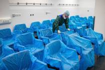 A nurse assembles plastic-wrapped chairs in a waiting area in the central emergency room of the ...
