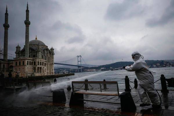 A municipality worker wearing a protective suit sprays water, backdropped by the Ottoman-era Me ...