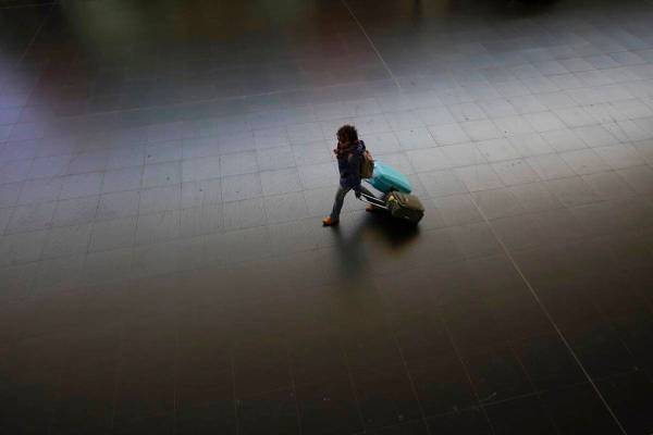 A passenger carries her luggage through an almost empty Termini main train station, in Rome, Mo ...