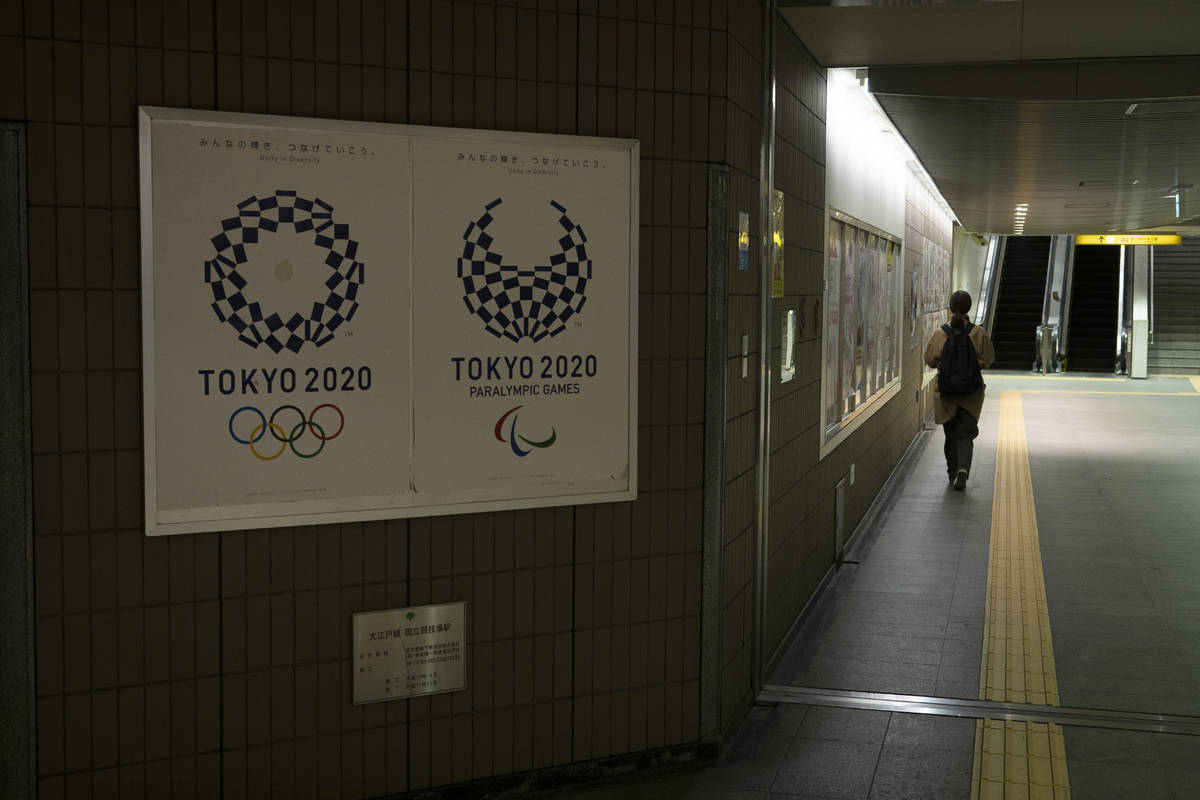 A commuter leaves a train station adorned with posters promoting the Tokyo 2020 Olympics in Tok ...