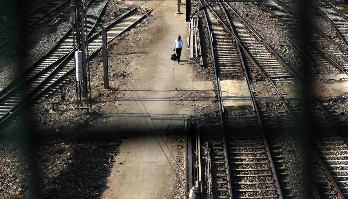 A passenger walks between railway tracks at New Delhi Railway station during a lockdown amid co ...