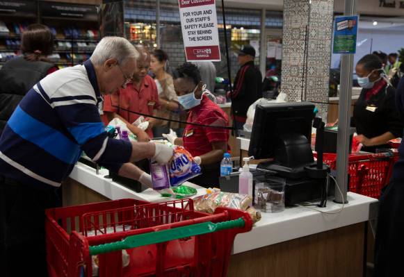 A screen divides a cashier, left, and customer right, at a pay point in a Spar supermarket, in ...
