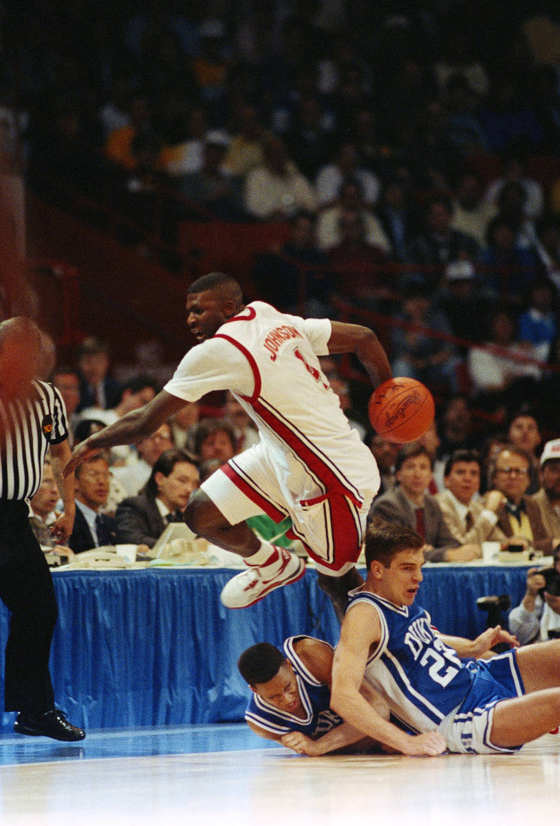 UNLV forward Larry Johnson keeps the ball in bounds behind his back while leaping over Duke pla ...