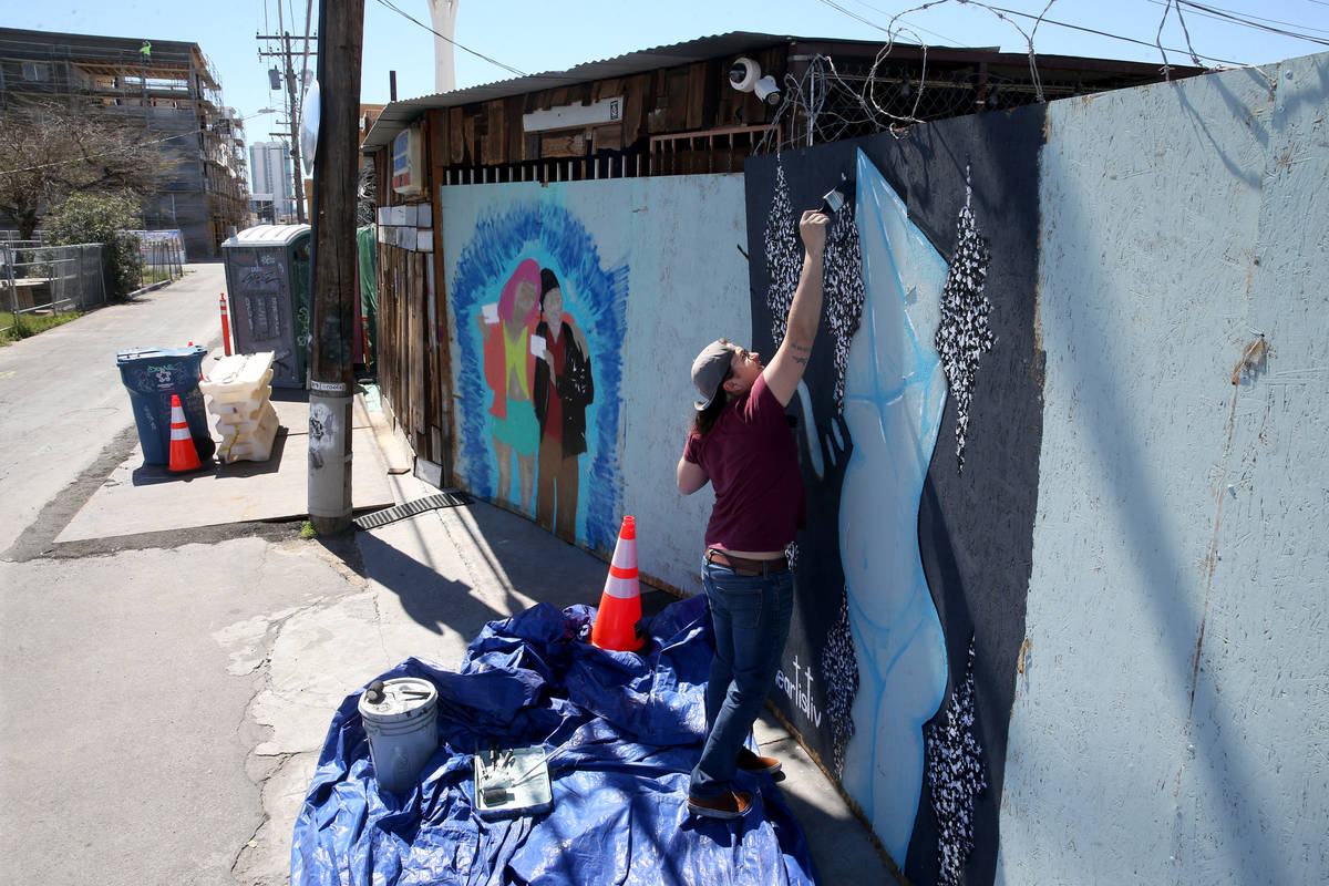 Artist R.J. Roberts paints a mural on the boarded up back door of ReBar in the Arts District in ...