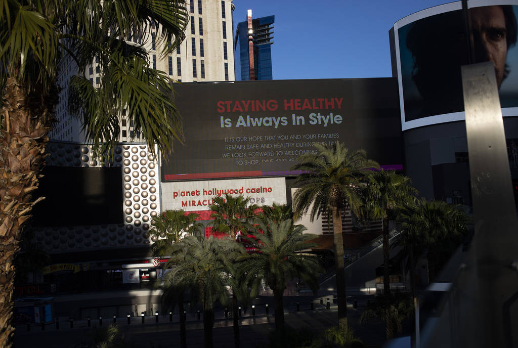 The sun begins to set on a marquee at Planet Hollywood that has a message of health and wellnes ...