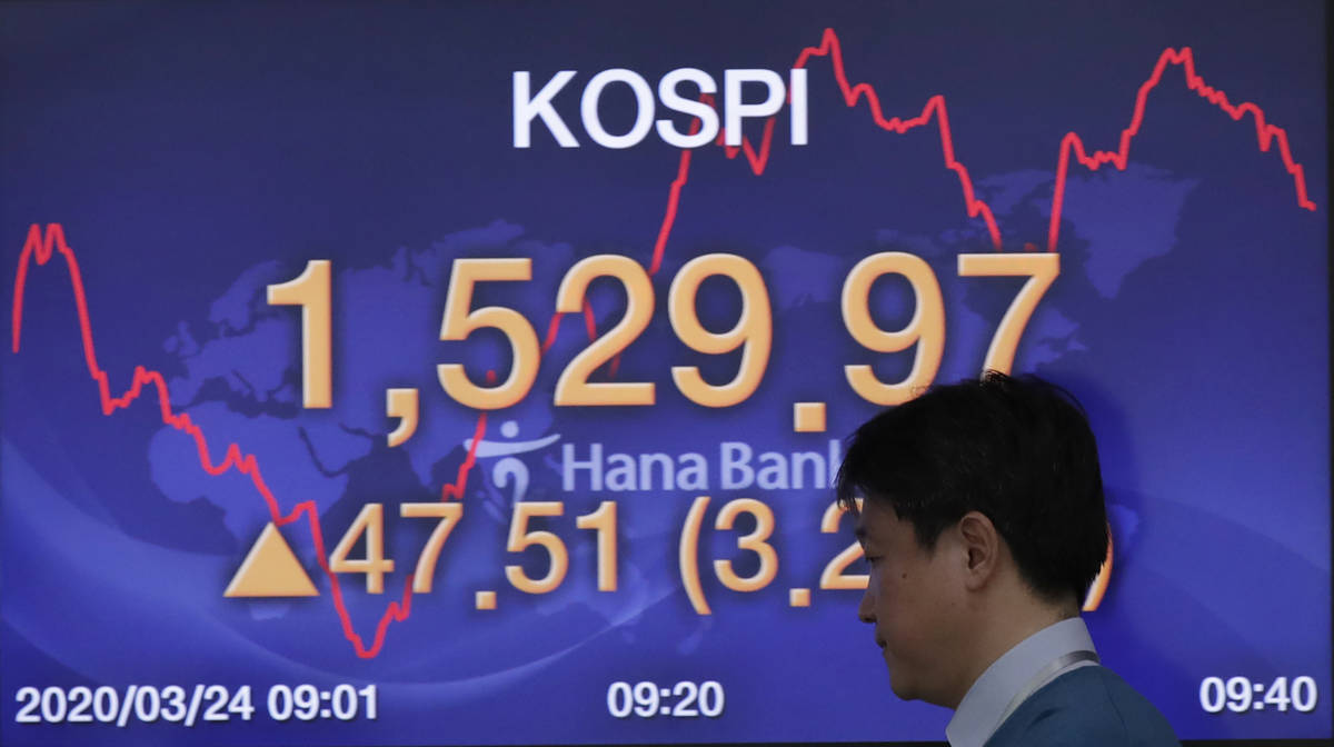 A currency trader walks by a screen showing the Korea Composite Stock Price Index (KOSPI) at th ...