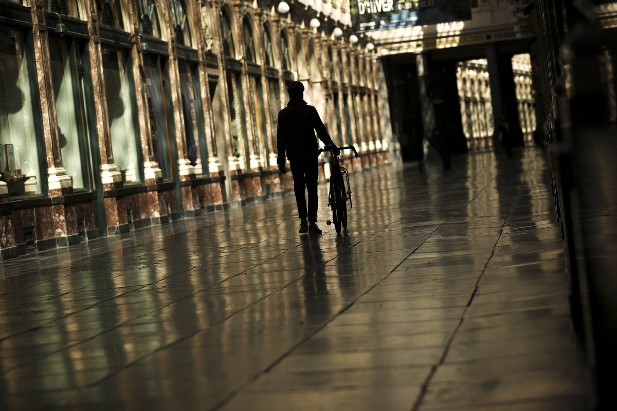 A man walks along along a virtually empty Royal Gallery of Saint Hubert commercial street durin ...