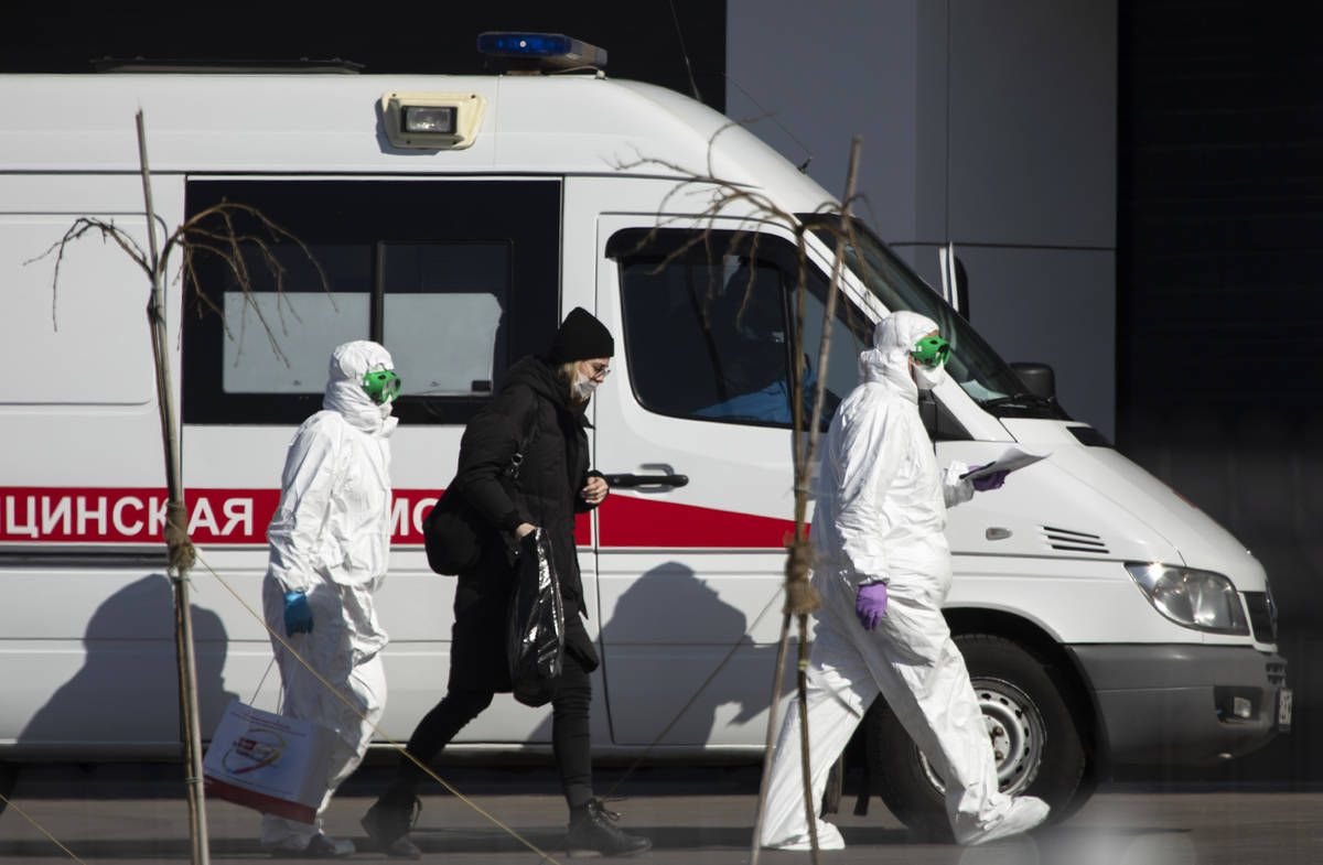 Medical workers escort a woman, suspected of having the coronavirus infection, to get out from ...